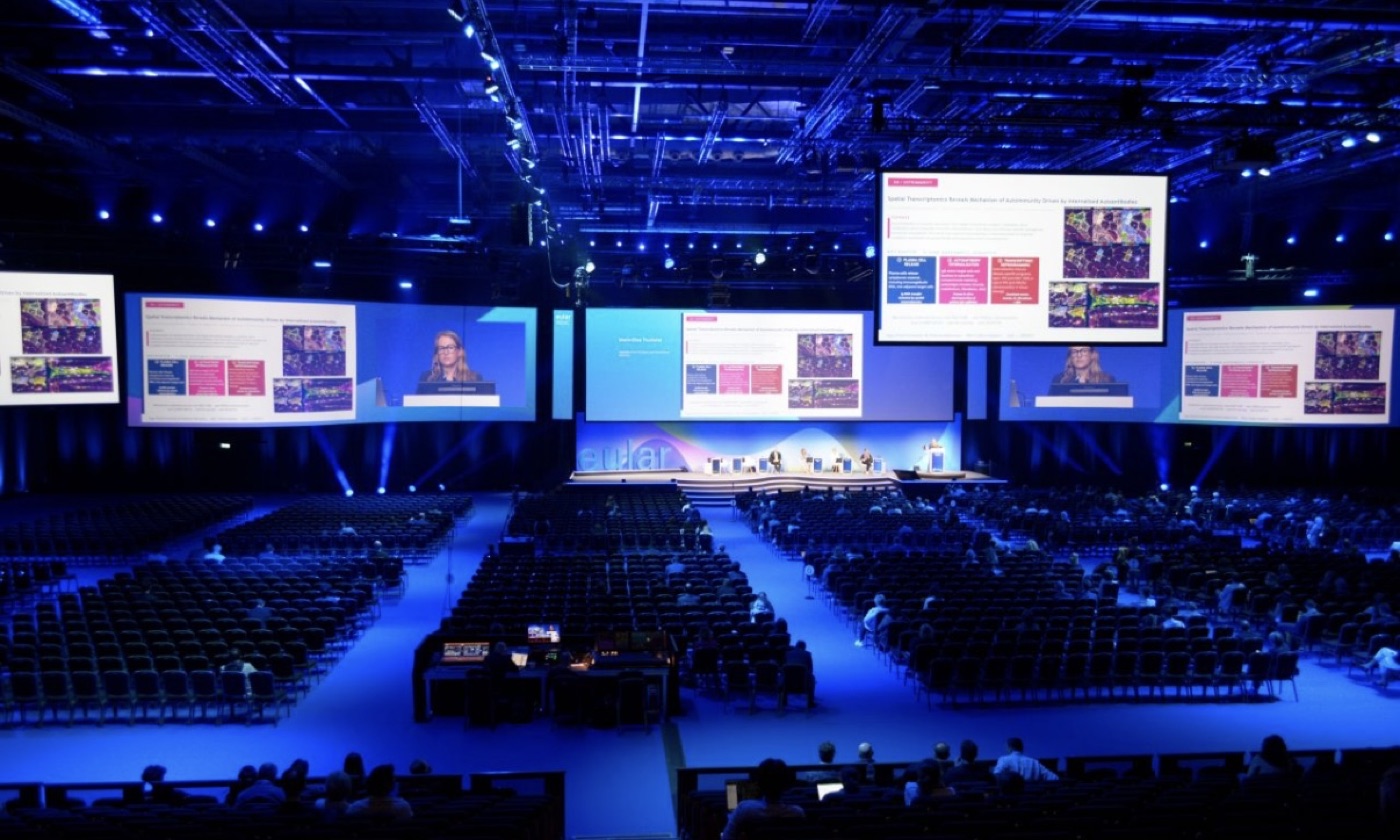 Audience seated facing the curved LED stage screen at EULAR 2026 London